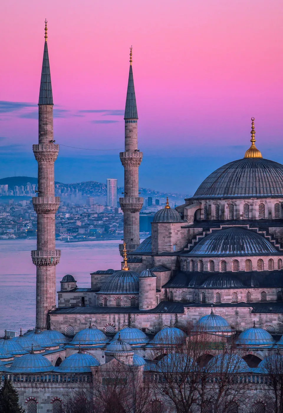 The Blue Mosque’s domes and minarets beneath a pink sunset sky in İstanbul.